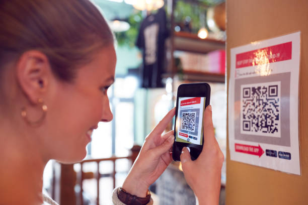 Woman With Mobile Phone Checking Into Venue Scanning QR Code During Health Pandemic stock photo