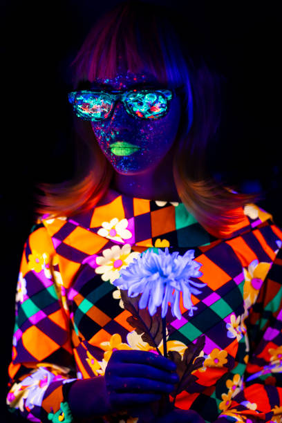 Woman with neon makeup holding flower in fluorescent colors Woman with neon makeup powder on face holding flower in fluorescent colors. paint neon color neon light ultraviolet light stock pictures, royalty-free photos & images