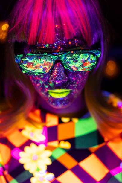 Woman with neon paint on face and colored sunglasses Woman with neon makeup powder on face in studio. Young woman painted with fluorescent make up. paint neon color neon light ultraviolet light stock pictures, royalty-free photos & images