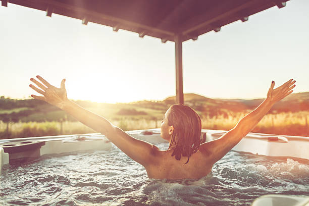 Woman with open arms in whirlpool hot tub Woman with open arms in whirlpool hot tub hot tub stock pictures, royalty-free photos & images