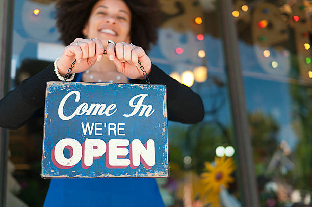 Woman with Open Sign Woman holding vintage open sign up outside of a boutique store front. Photograph taken in Grand Rapids, Michigan. small town stock pictures, royalty-free photos & images