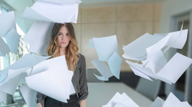 Woman with paper all around her in conference room Woman with paper all around her in conference room buried stock pictures, royalty-free photos & images