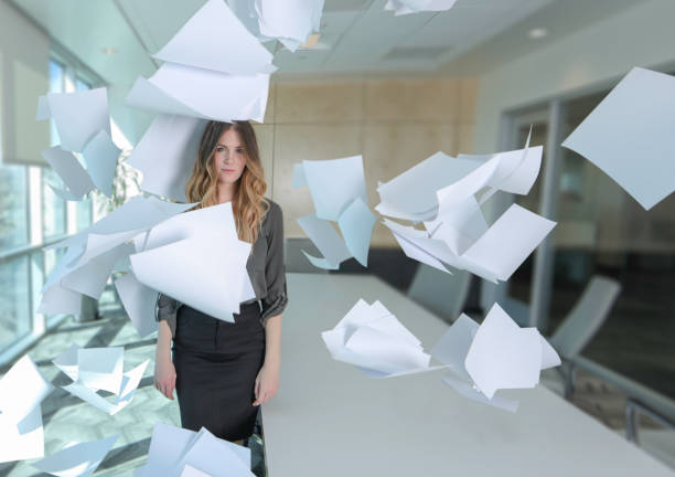Woman with paper all around her in conference room Woman with paper all around her in conference room buried stock pictures, royalty-free photos & images
