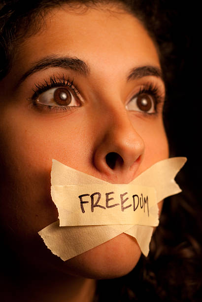 Woman with pieces of tape with the word freedom on her mouth Woman Scared to talk with tape over her mouth human mouth gag adhesive tape women stock pictures, royalty-free photos & images