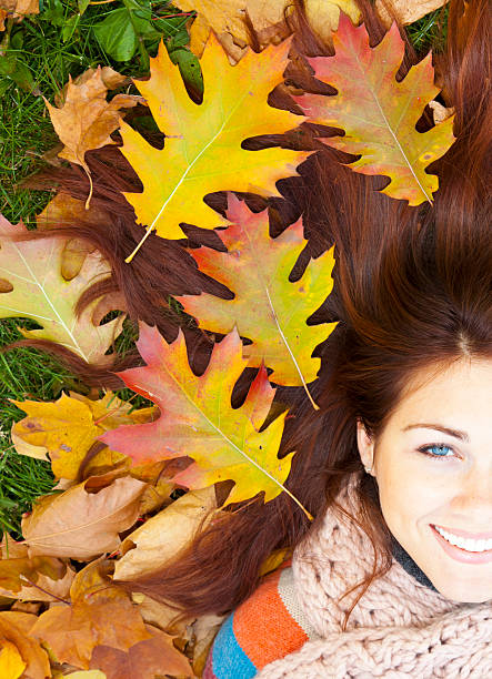 Woman with red hair laying on autumn leaves. stock photo