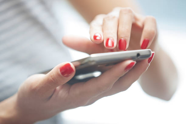Woman with red manicure using smartphone stock photo