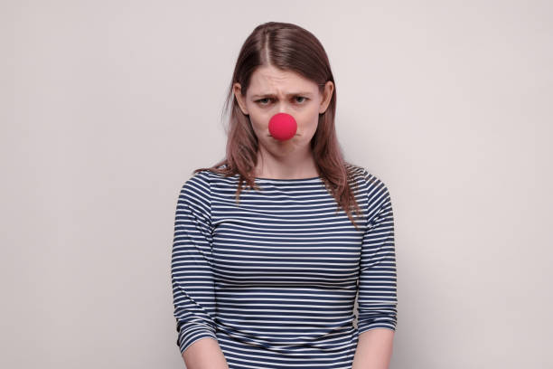 woman with red nose looking angry and frustrated Beautiful woman with red nose looking angry and frustrated being offended. Studio shot on white background. clown's nose stock pictures, royalty-free photos & images