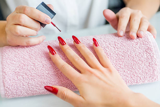 A woman with red painted nails getting a manicure Woman doing a manicure artificial nail stock pictures, royalty-free photos & images