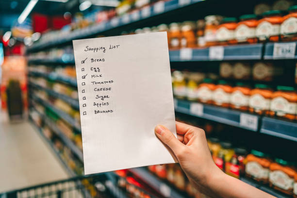 Woman with shopping list in grocery store stock photo