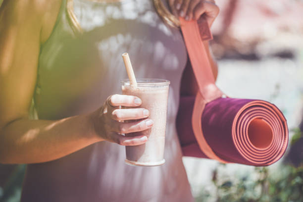 Woman with smoothie and yoga mat stock photo