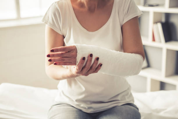 Woman with trauma Cropped image of beautiful mature woman with her arm in gypsum sitting at the traumatologist bone fracture stock pictures, royalty-free photos & images