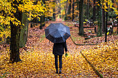 istock Woman with umbrella walks between tombstones in rain 1286708925