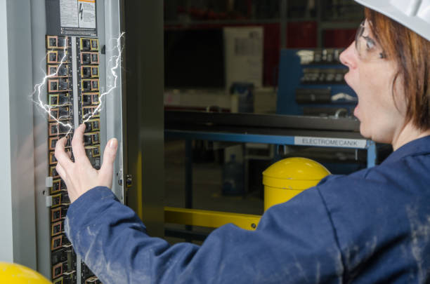 Woman worker being electrocuted at a fuse box stock photo