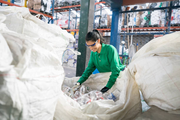 Woman working in a recycling factory Woman working in a recycling factory sorting some bottles and looking very happy - environmental concepts plastic stock pictures, royalty-free photos & images