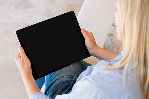Woman working on tablet High view of woman working on digital tablet with black screen. Mature woman sitting on couch and using laptop. Close up of woman surfing net with digital tablet. streaming service stock pictures, royalty-free photos & images