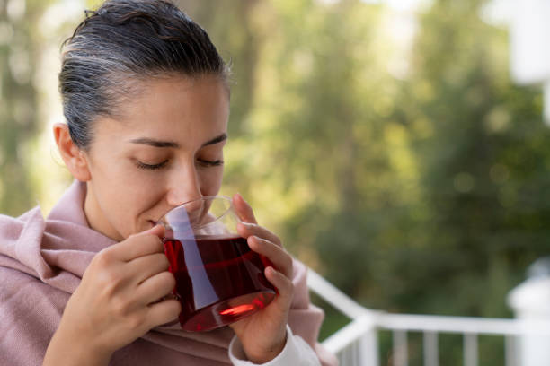 kvinna insvept i filt dricka varm bryggt rött te. te för immunitet, ingredienser för behandling av förkylningar. - shodography bildbanksfoton och bilder
