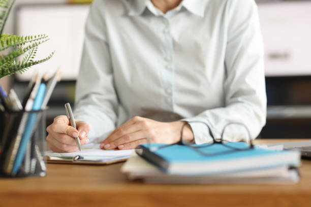 Woman writes with pen in documents at workplace stock photo