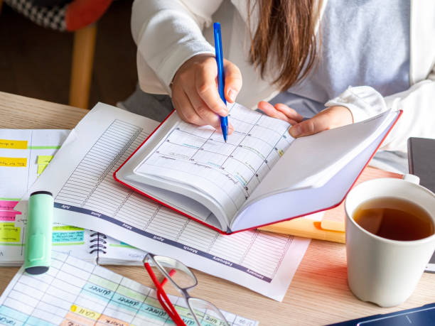 woman writing schedule In calendar notebook on a desk stock photo
