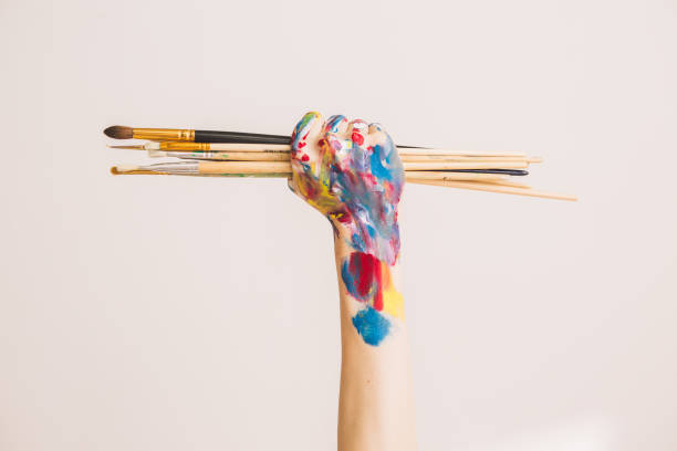 kvinnans konstnärs knytnäve i färger med penslar isolerade på en vit bakgrund. konceptfotografering för annons- eller konstblogg - palettblad bildbanksfoton och bilder