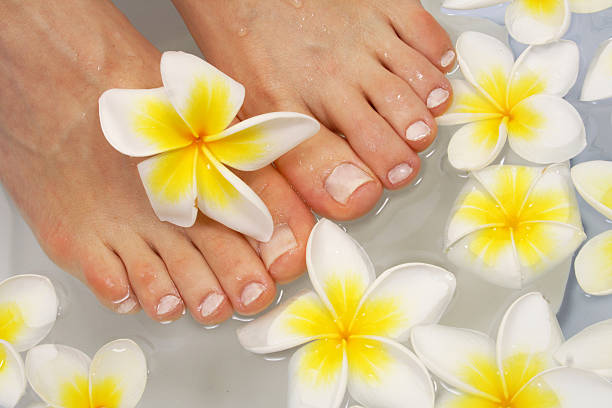 woman's feet in bath with frangipani therapy stock photo