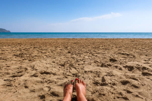 A woman's feet in the sand on a beach A woman's feet in the sand on a beach. Concept for traveling to tropical / exotic places, vacation and holiday. human feet buried in sand. summer beach stock pictures, royalty-free photos & images
