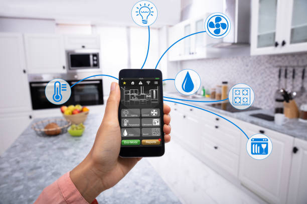 Woman's Hand Holding Mobile Phone Woman's Hand Using Home Control System On Cellphone With Various Icons In The Kitchen home automation photos stock pictures, royalty-free photos & images