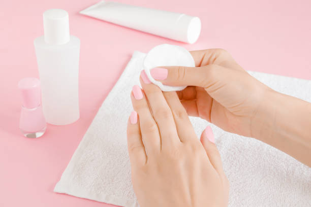 vrouw de hand te verwijderen roze nagellak met witte wattenschijfje op de handdoek. close-up. - nail polish bottle close up stockfoto's en -beelden