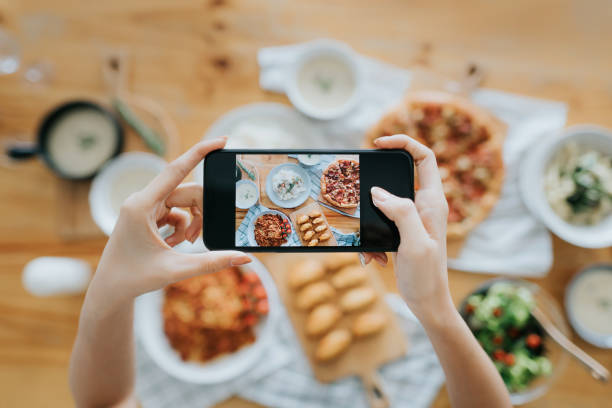 mano de mujer tomando fotos de comida en la mesa con teléfono inteligente durante la fiesta con amigos - bloguear fotos fotografías e imágenes de stock