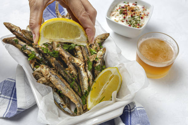Woman's hand with fried anchovies with lemon and parsley stock photo