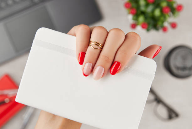 Womans hand with trendy manicure holding notepad over table. Manicure design trends stock photo