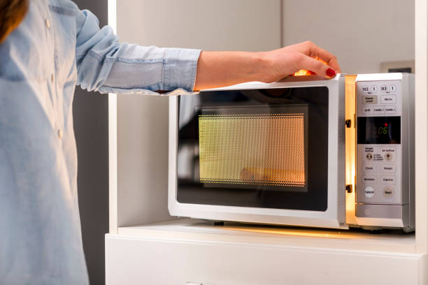 A Woman's Hands Closing Microwave Oven Door stock photo