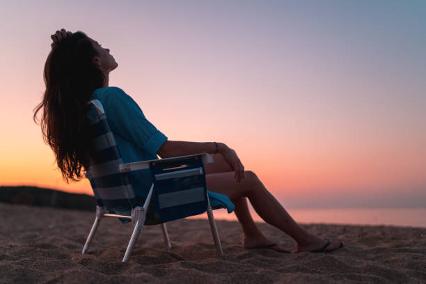 women at the beach relaxing at sunset during golden hour women at the beach at sunset during golden hour. Fun and friendship outdoors. golden hour stock pictures, royalty-free photos & images