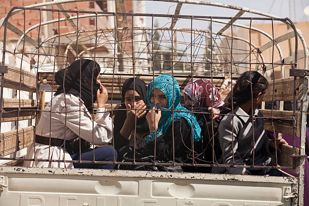 Women behind bars Tozeur, Tunisia - March 30, 2013: Several young women, dressed in typical tunisian clothing with head scarves, are sitting on the back of a van behind bars tunisia woman stock pictures, royalty-free photos & images