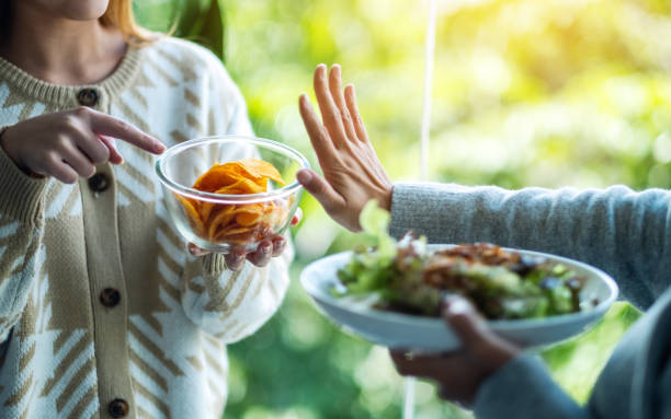 Women choosing to eat vegetables salad and making hand sign to refuse potato chips Women choosing to eat vegetables salad and making hand sign to refuse potato chips avoidance stock pictures, royalty-free photos & images