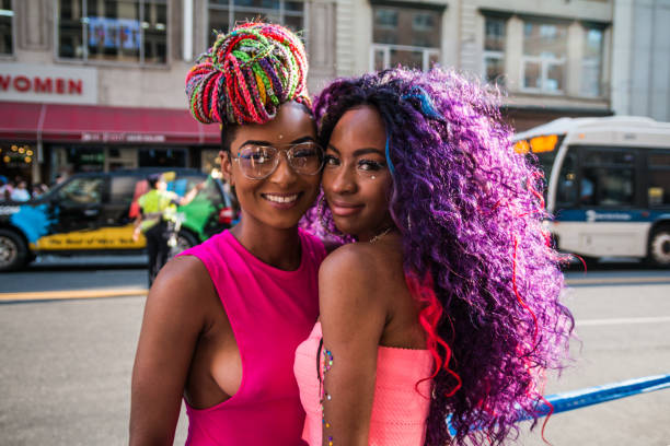 Women couple smiling at NYC Pride Parade Women couple in colorful hair and outfits smiling while waiting for the annual NYC Pride Parade. nyc pride parade stock pictures, royalty-free photos & images