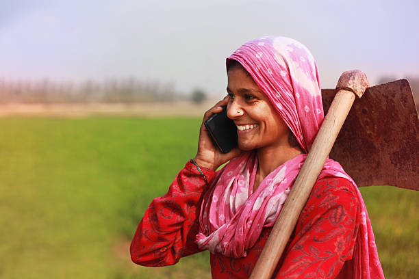 Women farmer talking on smart phone Cheerful traditional Village women standing in green wheat field and talking on the mobile phone. She looking so happy when she talking on the phone.  haryana stock pictures, royalty-free photos & images