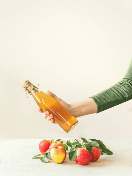 Women hand holding bottle with homemade apple cider vinegar stock photo