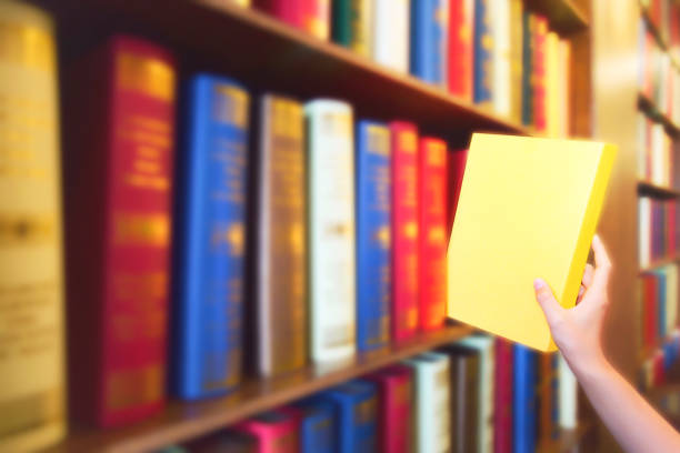 kvinnor hand dra gul bok från trä bokhyllor i offentligt bibliotek. färgglada böcker, lärobok, literatur på bokhyllan. - sj bildbanksfoton och bilder