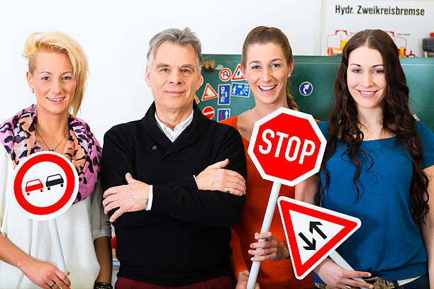 women in a driving class holding signs with a male teacher - trafiklärare bildbanksfoton och bilder