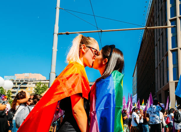donne che si baciano al gay pride marciando sostenendo l'uguaglianza e i diritti legali per la comunità lgbtqi - pride milano foto e immagini stock
