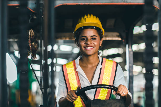 안전 정장과 헬멧 행복한 미소와 지게차 드라이버 위치에서 여성 노동자는 산업 공장 물류 배송 창고에서 일을 즐길 수 있습니다. - labor day 뉴스 사진 이미지