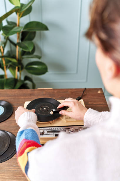Women listening to music with retro turntable on table Women listening to music with retro turntable on table record analog audio stock pictures, royalty-free photos & images