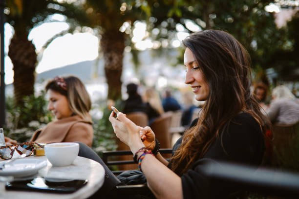 women relaxing and texting in the beach cafe stock photo