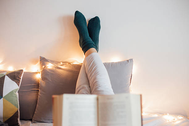 Women relaxing in bad and reading a book stock photo