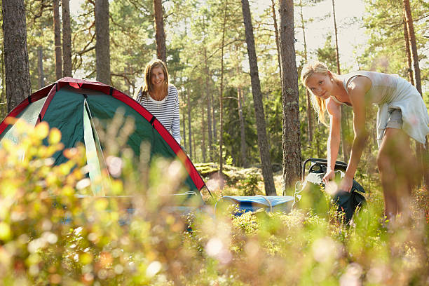 женщины настройка лагеря в лесу - setting up camping tent стоковые фото и и...