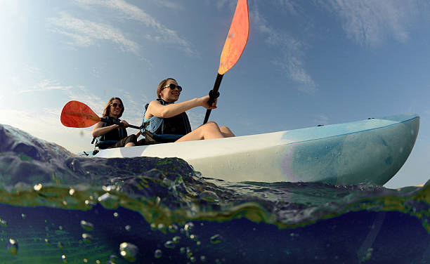 women smiling in blue kayak on tropical ocean stock photo