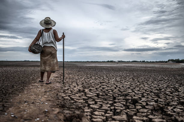 Women standing on dry soil and fishing gear, global warming and water crisis stock photo