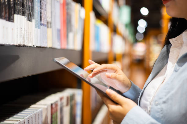 Women using digital tablet in library stock photo