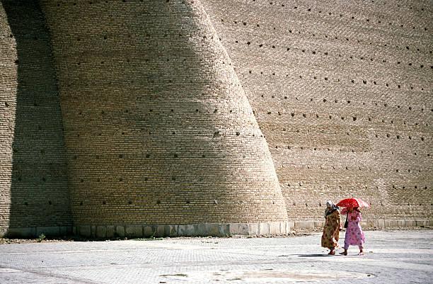Women walking in front of a large wall, Buchara, Uzbekistan "Women walking in front of a large wall, Buchara, UzbekistanMore images of same photographer in lightbox:" bukhara stock pictures, royalty-free photos & images