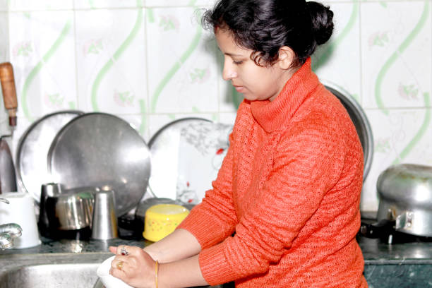 Women washes dishes in kitchen stock photo